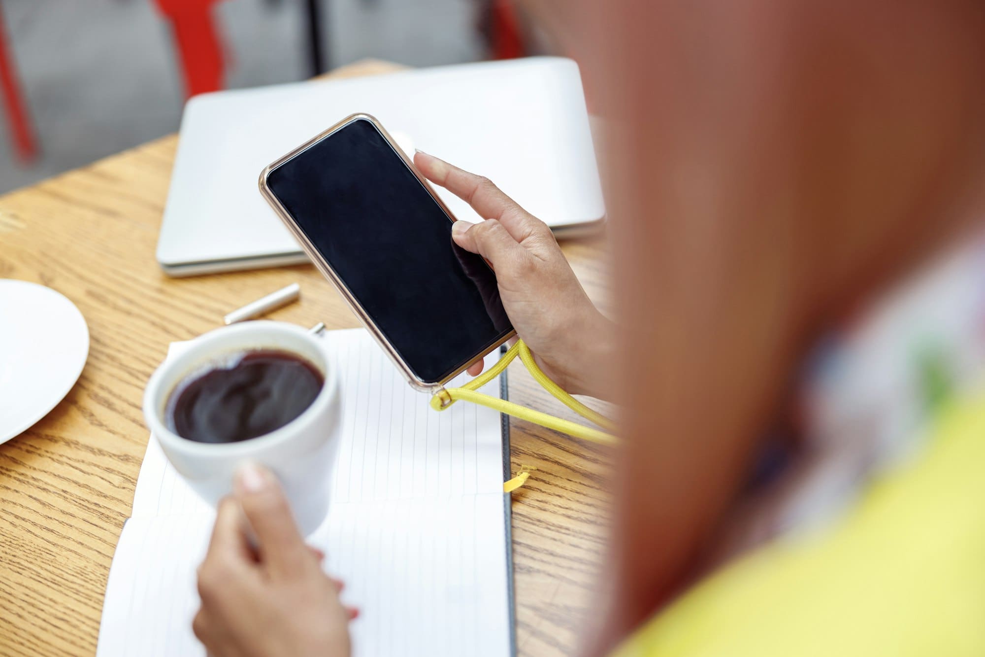 Person looking at smartphone while raising coffee cup