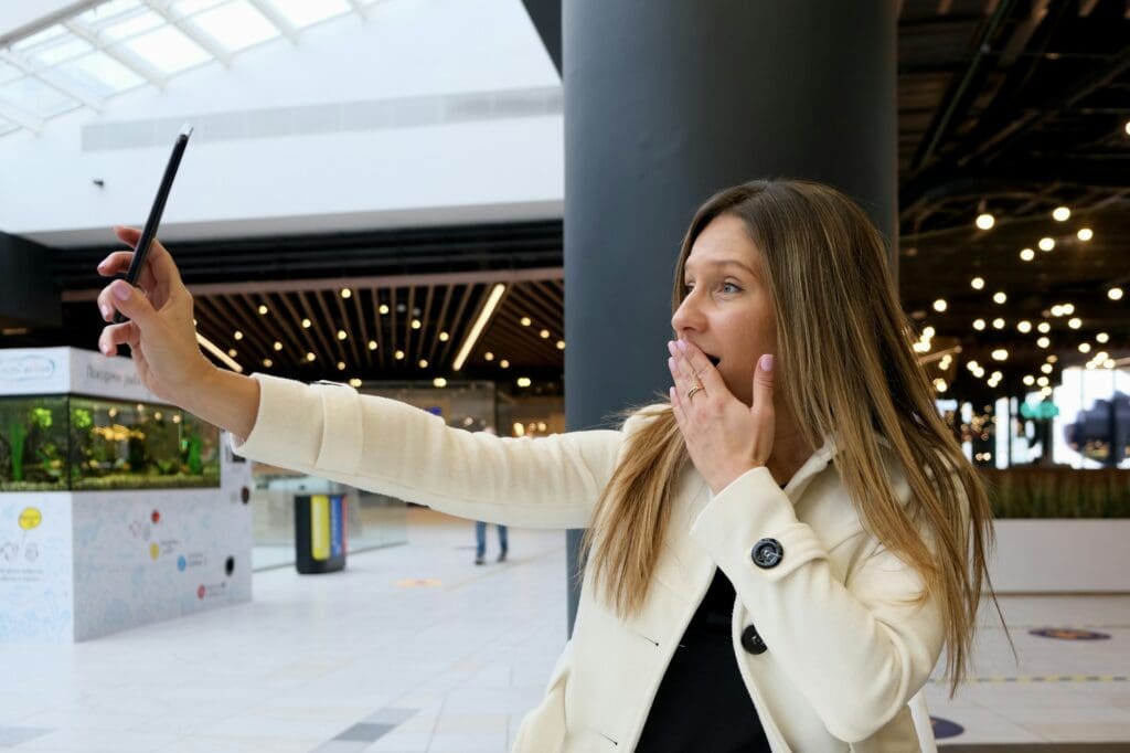 A young woman takes a selfie in a cafe.