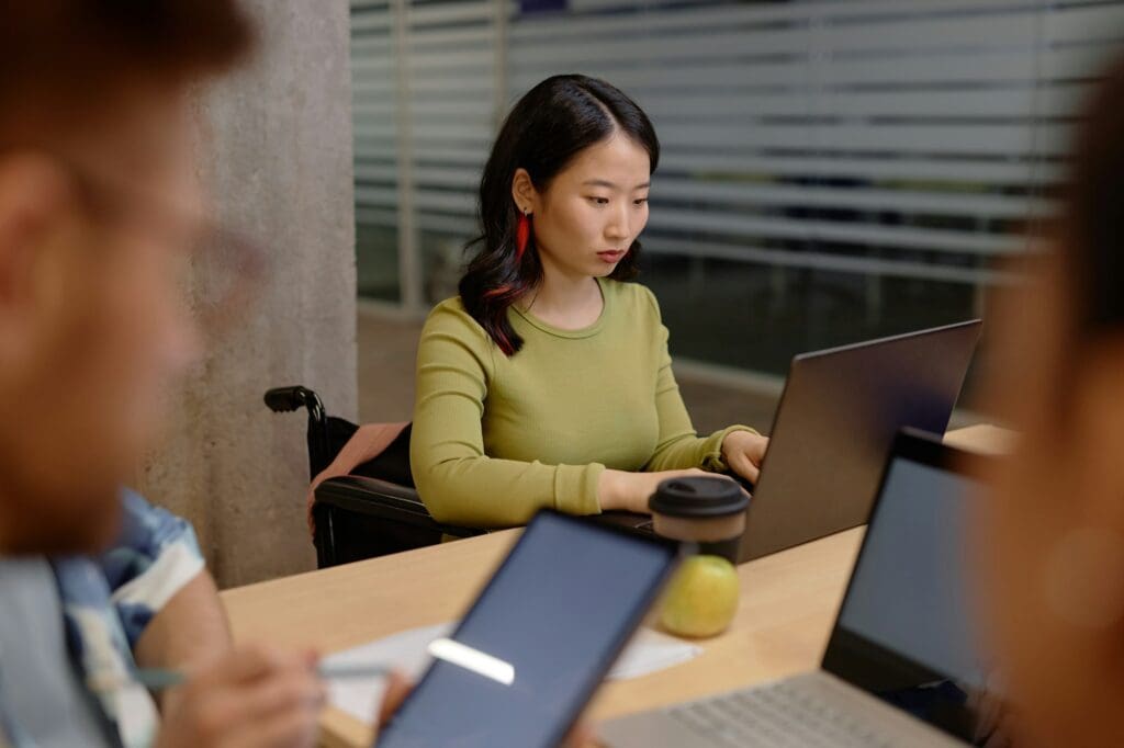 Wheelchair User Writing on Computer at University Class